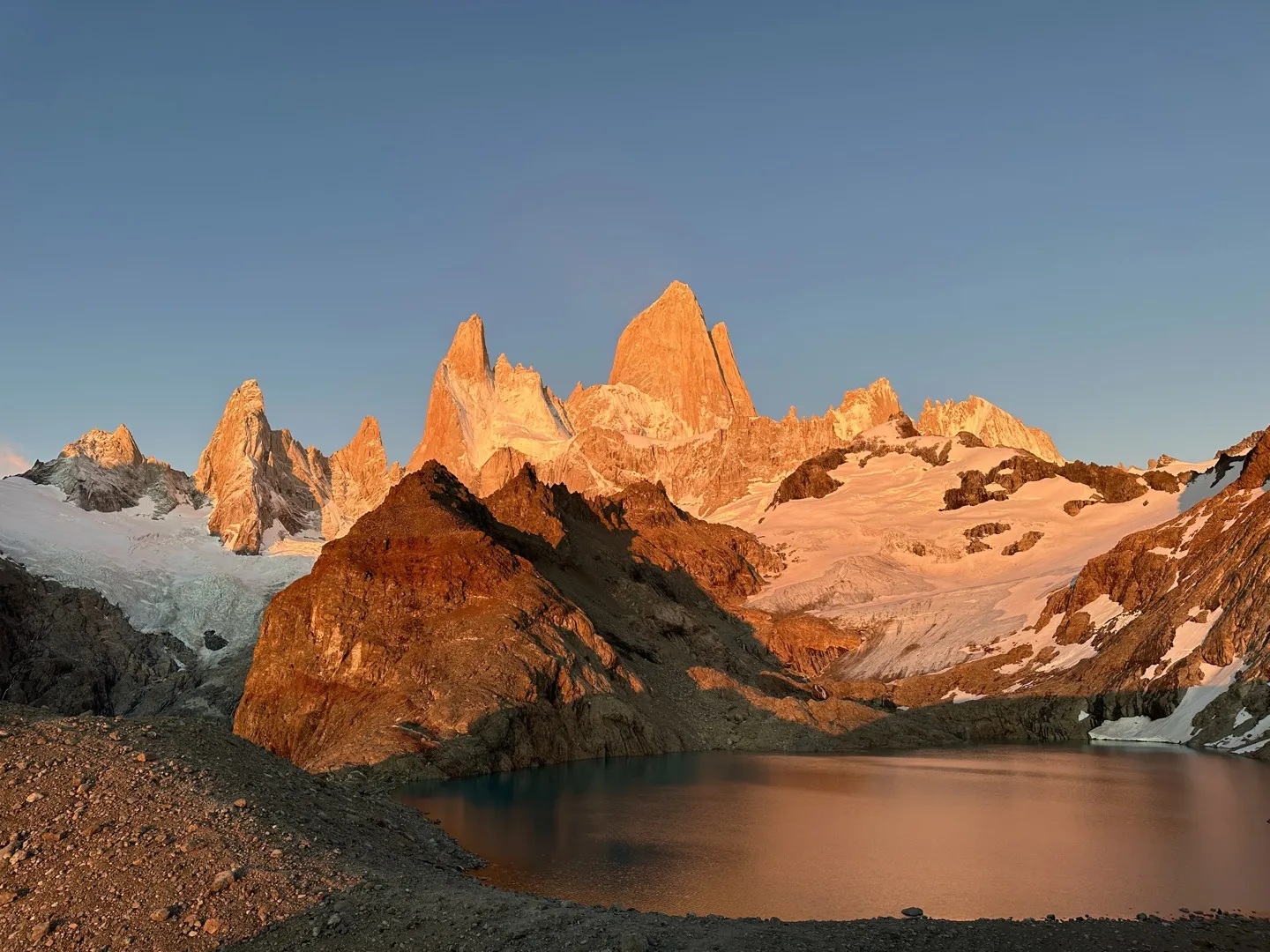 Fitz Roy glowing orange at sunrise, reflected in the still water of Laguna de los Tres
