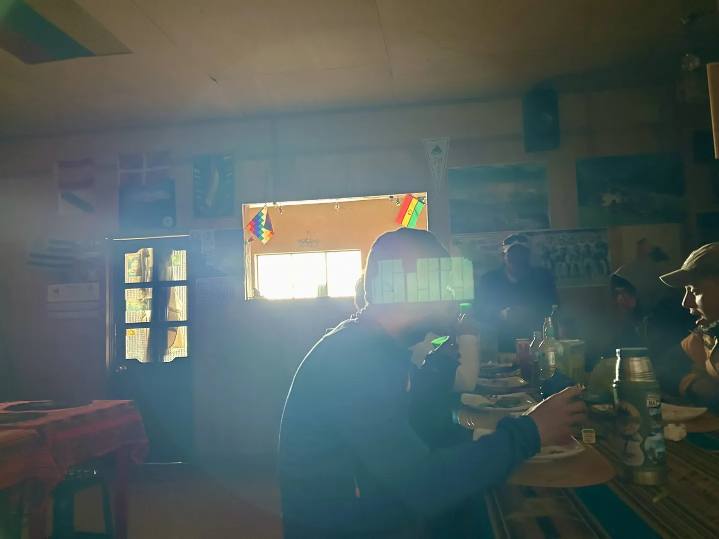 Climbers eating at long tables in the Huayna Potosi low camp refuge, sunlight through the window