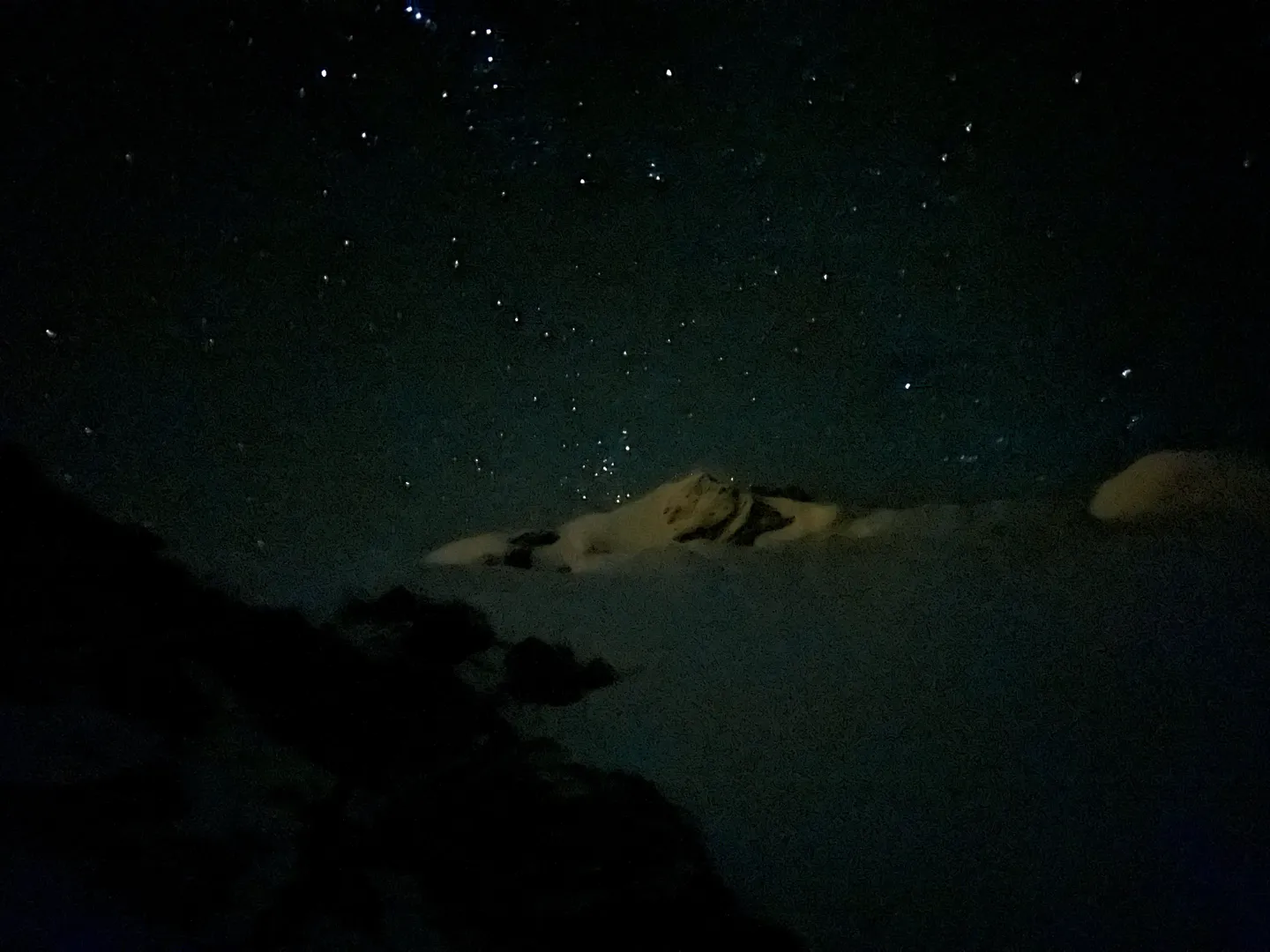 A star-filled sky over snow-covered rock in the middle of the night on Huayna Potosi