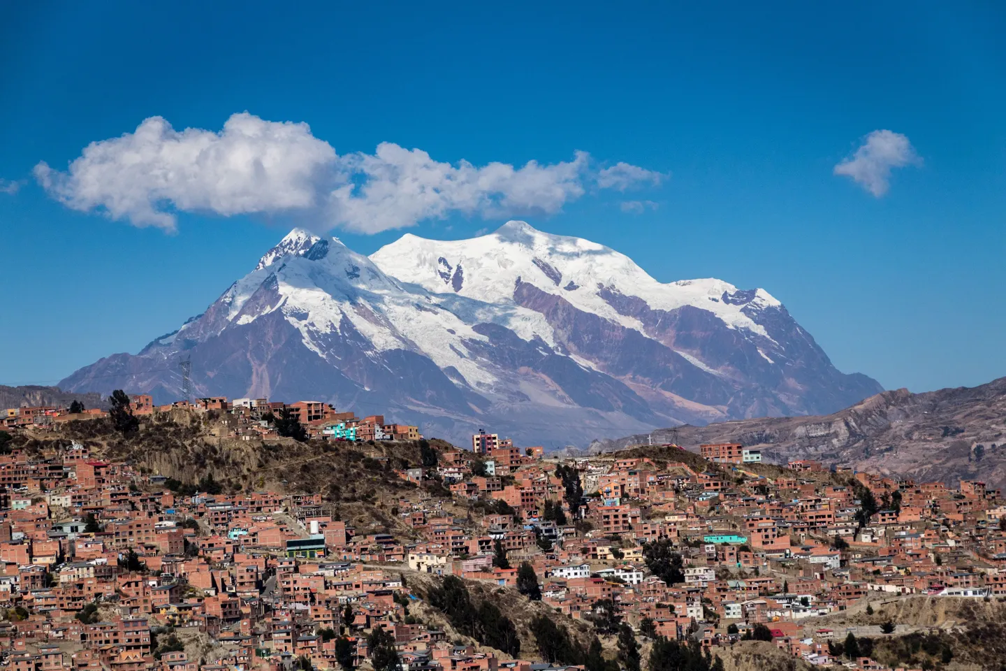 A snow-capped peak rising behind the red-brick houses stacked up the hillsides of La Paz