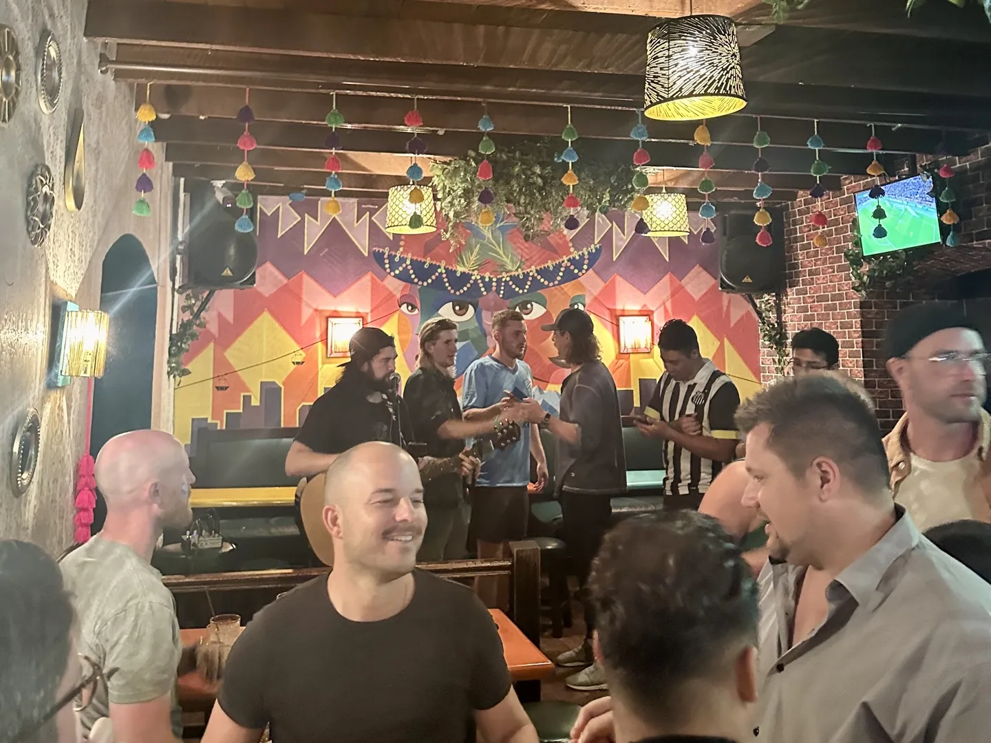 Travellers drinking in front of a painted mural in a La Paz party hostel bar