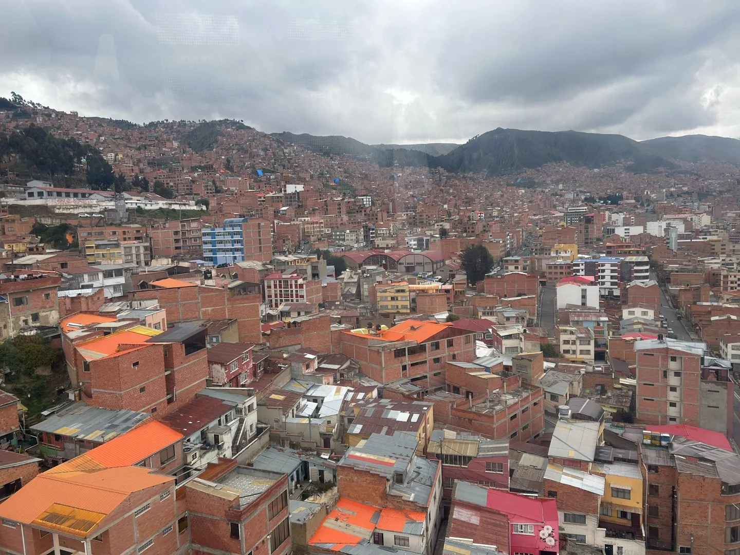 Orange rooftops of La Paz stacked across the hillside below the clouds