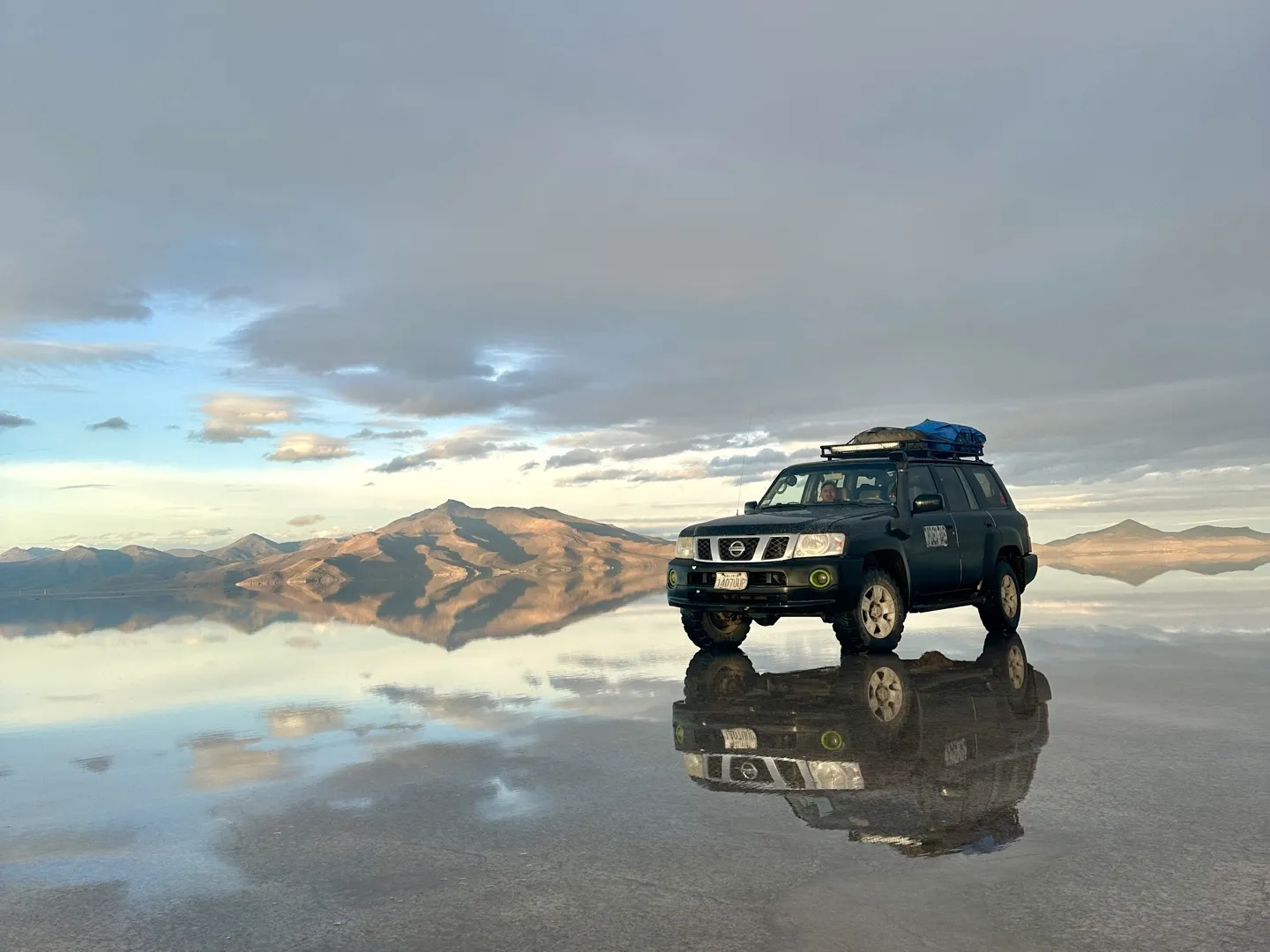 The tour 4WD parked on the flooded Salar de Uyuni with the mountains and sky reflected beneath it