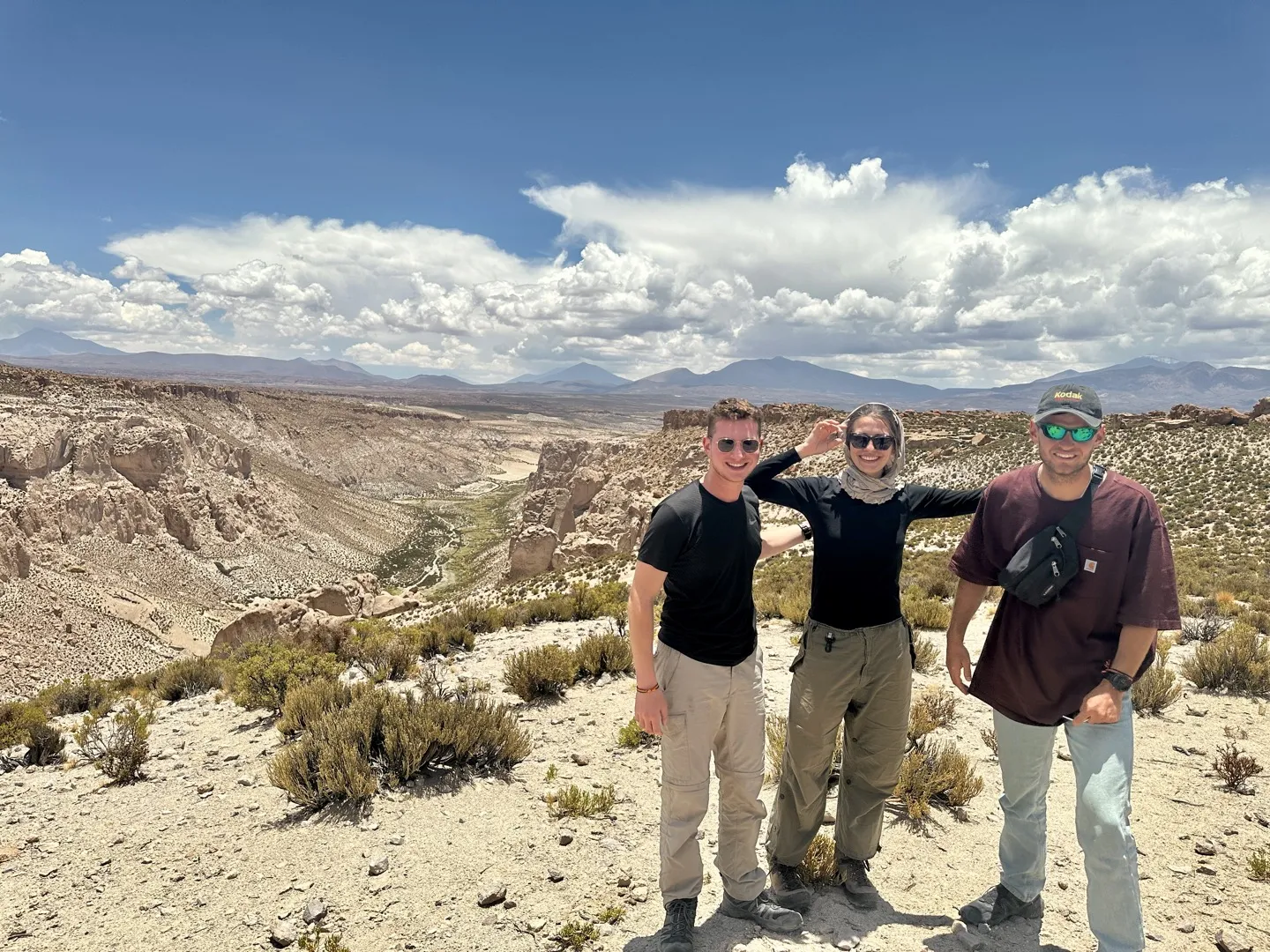 Three travellers at the Canon de la Anaconda viewpoint with the canyon winding away behind them