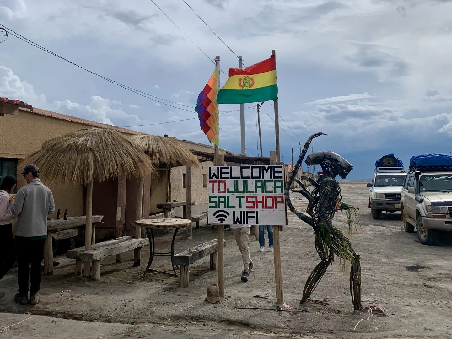 The Welcome to Julaca Salt Shop sign, a scrap-metal sculpture and tour 4WDs parked outside