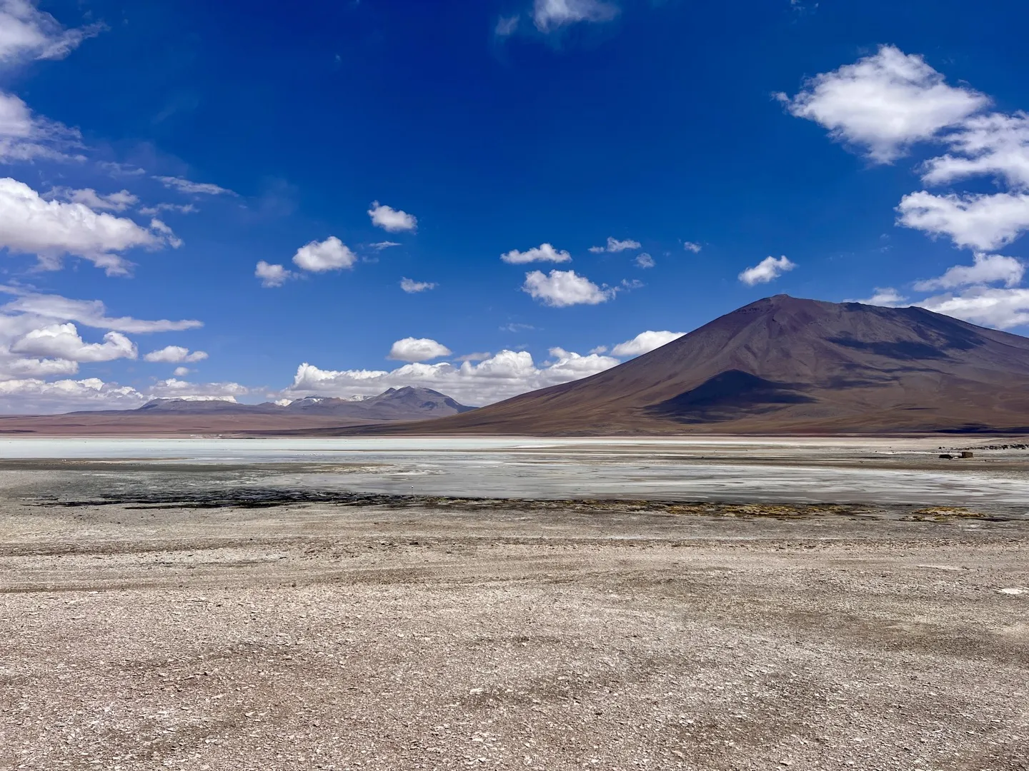 The pale water of Laguna Blanca in front of the cone of Licancabur Volcano on a clear day