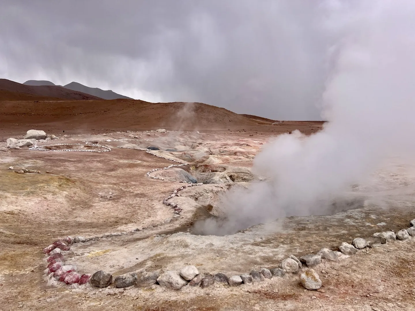Steam rising from the Sol de Manana geysers, with a rope of stones marking the path around the vents