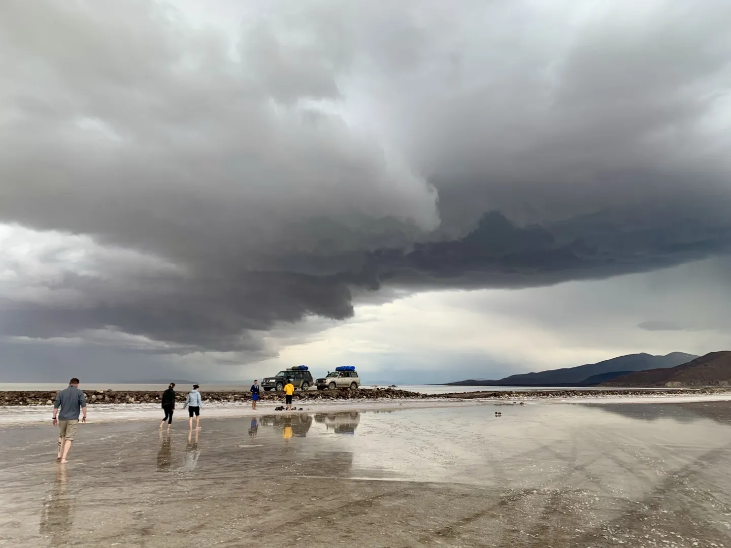 Dark storm clouds rolling over the flooded edge of the Salar de Uyuni as the group walks back to the 4WDs