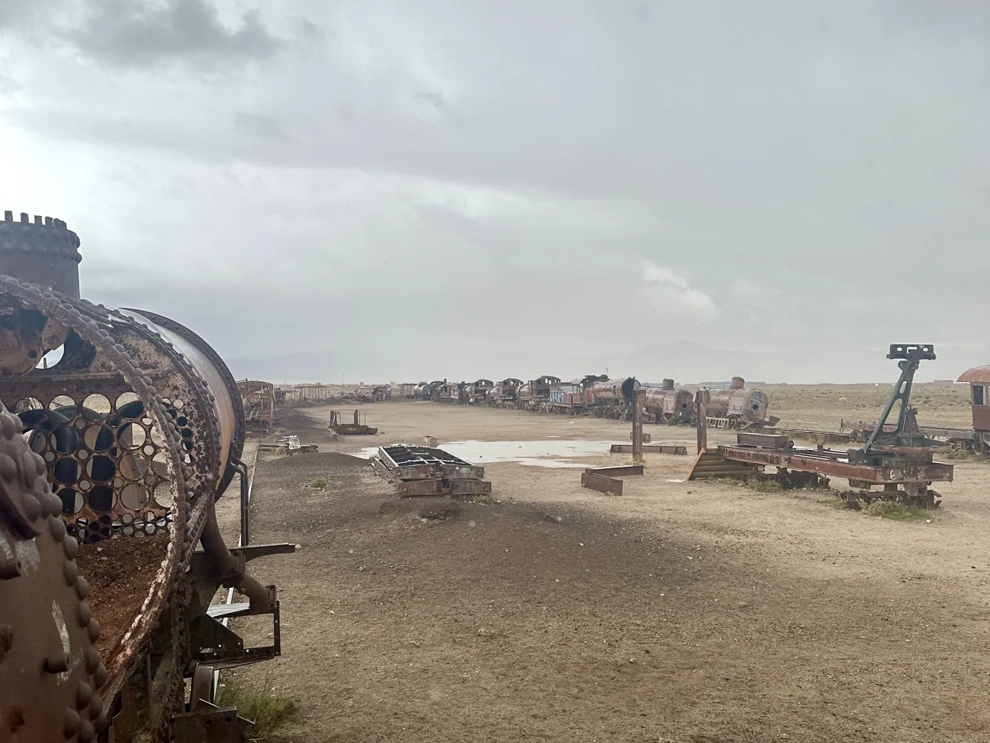 Rusting steam locomotives lined up under a grey sky at the Train Cemetery outside Uyuni