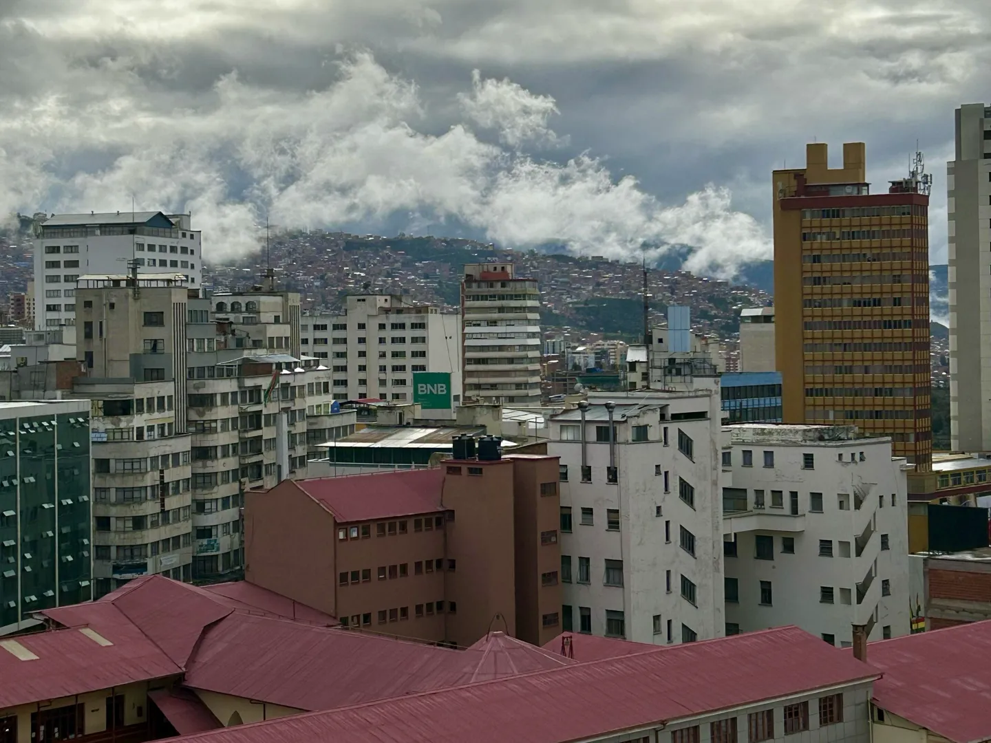 High-rise blocks and red rooftops of central La Paz with cloud spilling over the valley rim