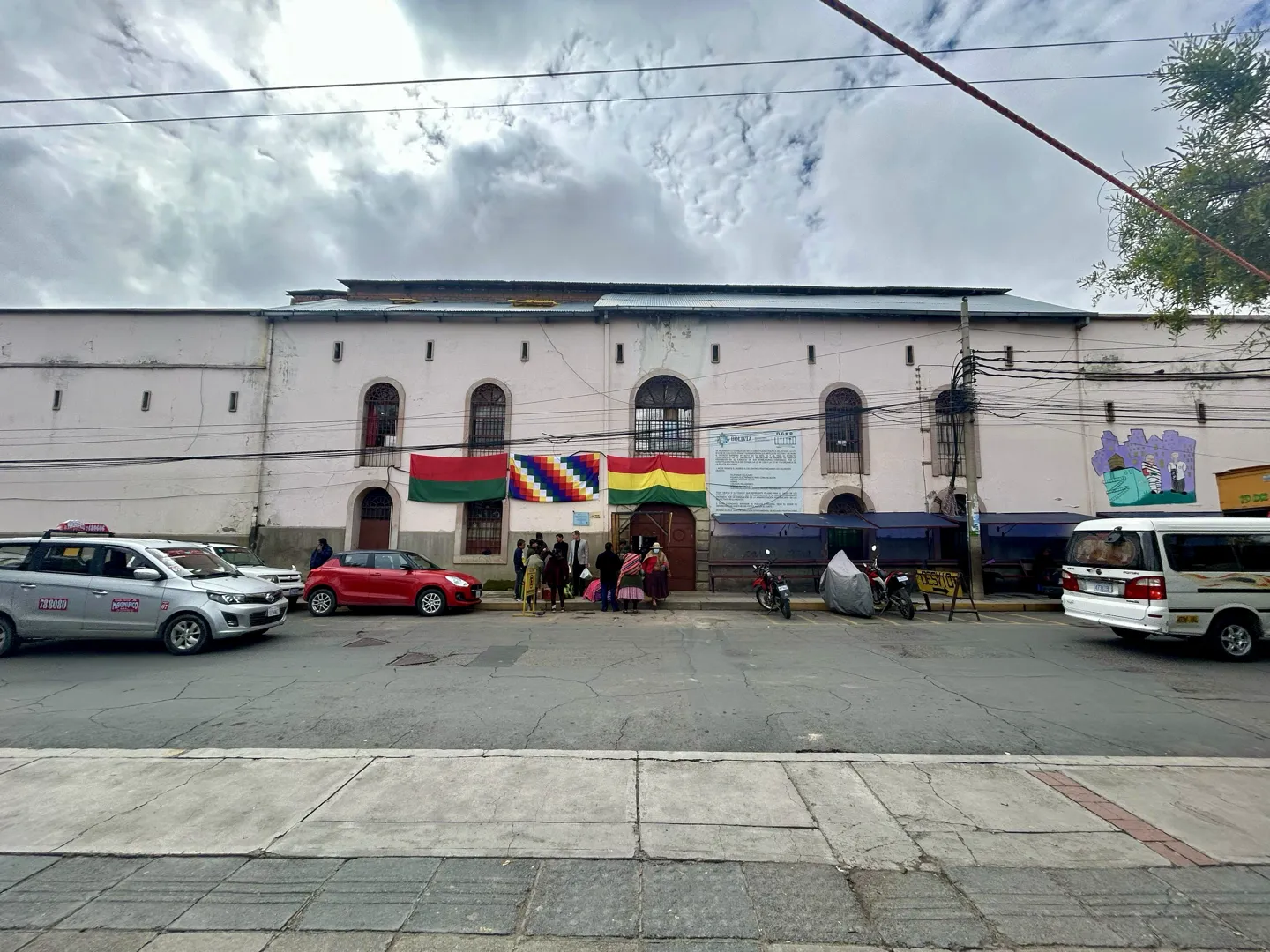 The long colonial facade of San Pedro Prison in the centre of La Paz, with taxis parked on the street outside