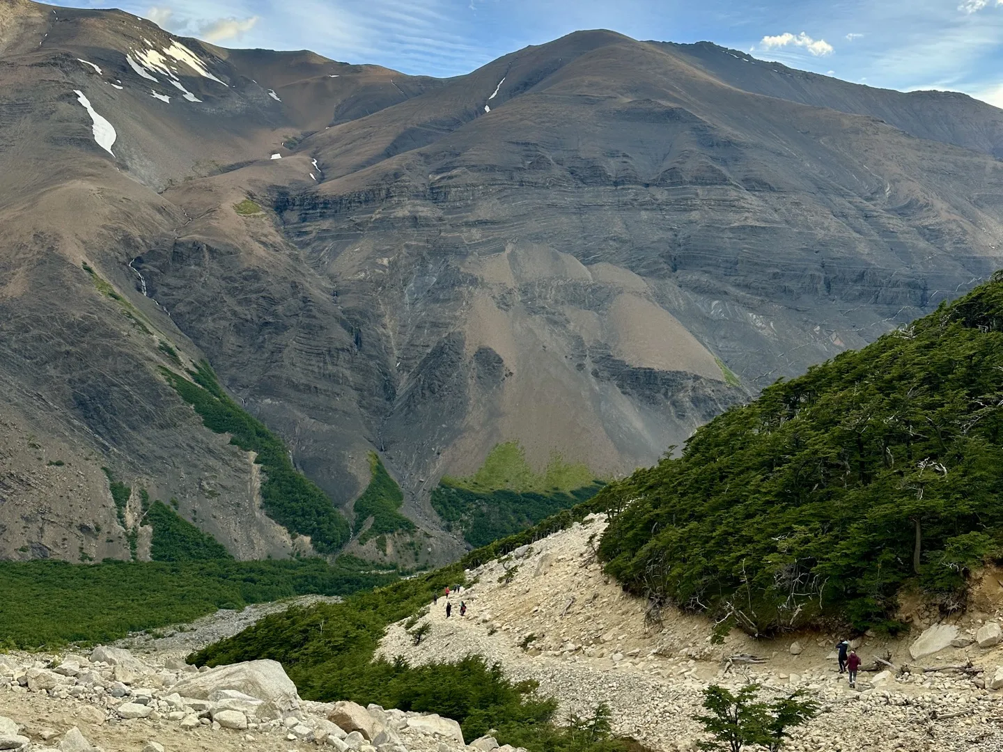 Hikers heading down the loose moraine below Mirador Base Torres after sunrise