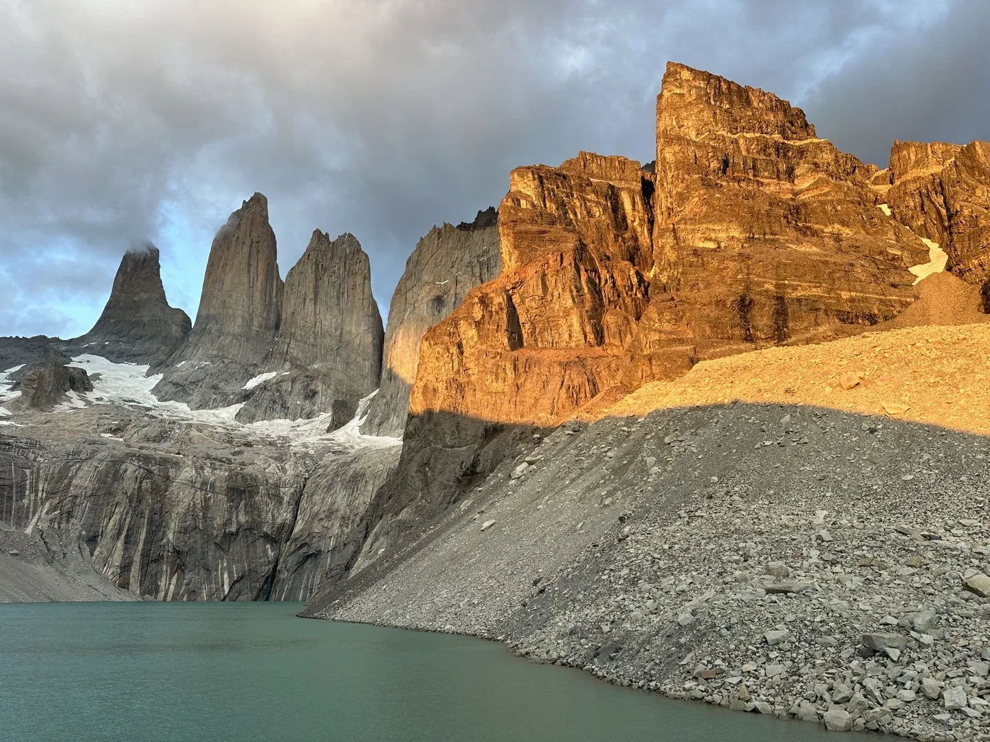 Sunrise light glowing orange on the cliffs beside the three towers at Mirador Base Torres