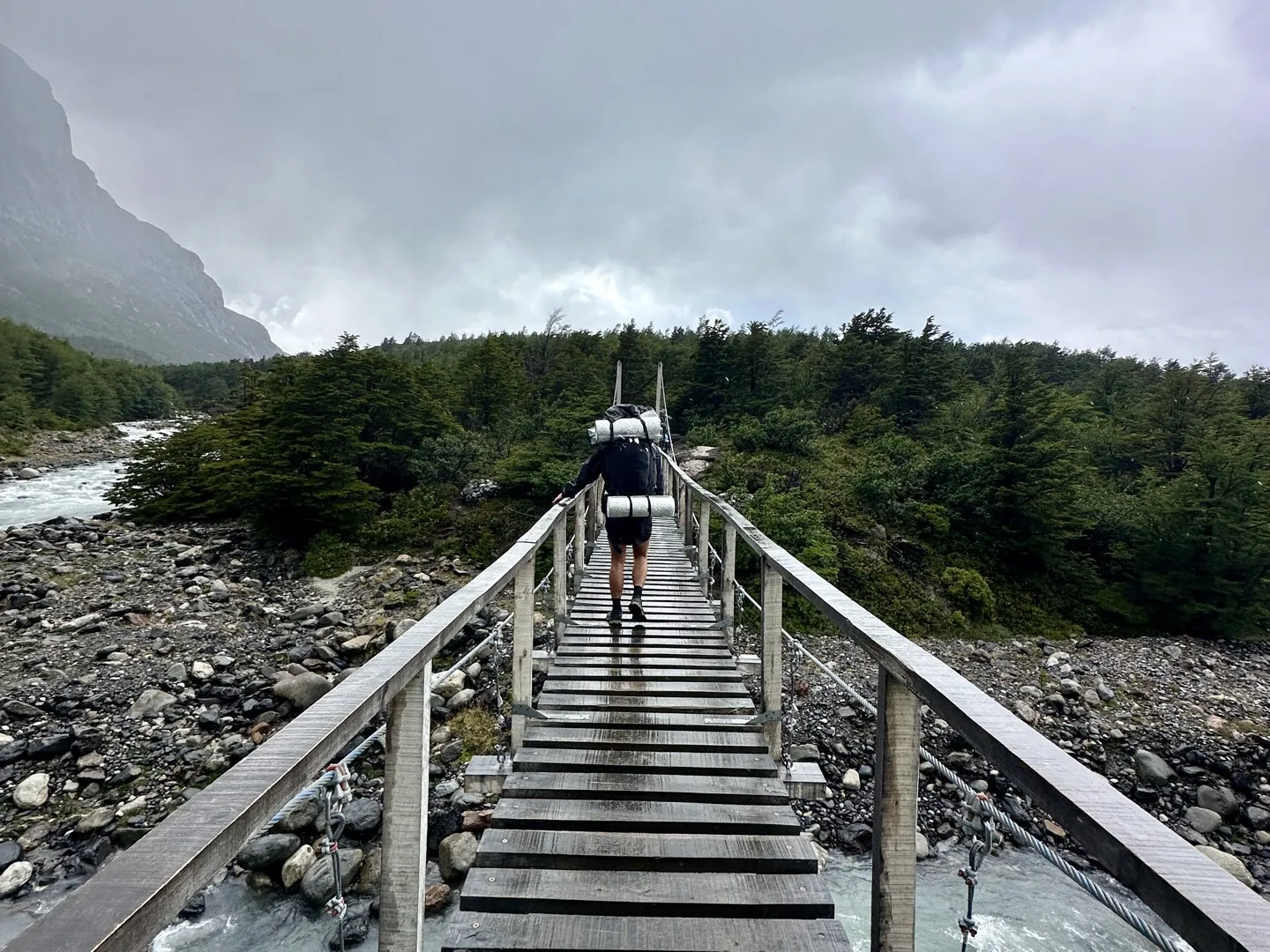 Hiker with a full pack crossing the suspension bridge over the Río del Francés near Italiano