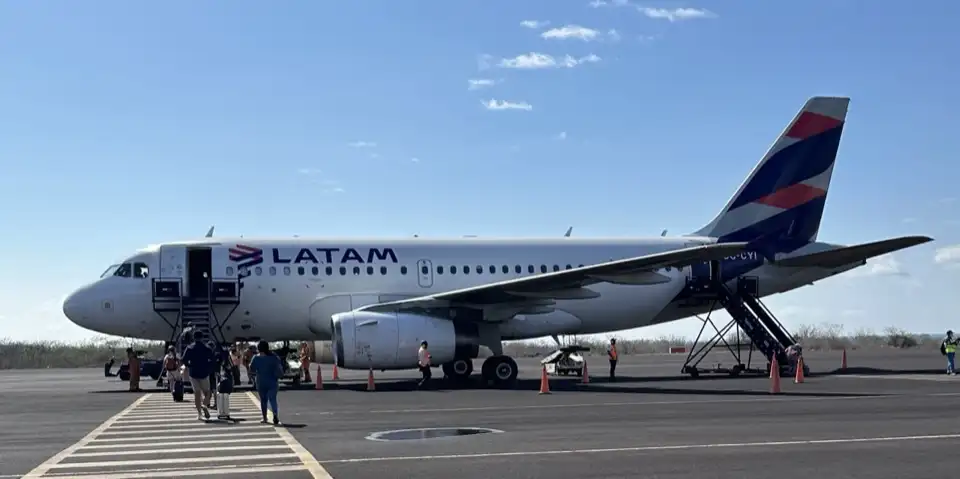 A LATAM plane on the apron at San Cristóbal Airport, with passengers walking out to board