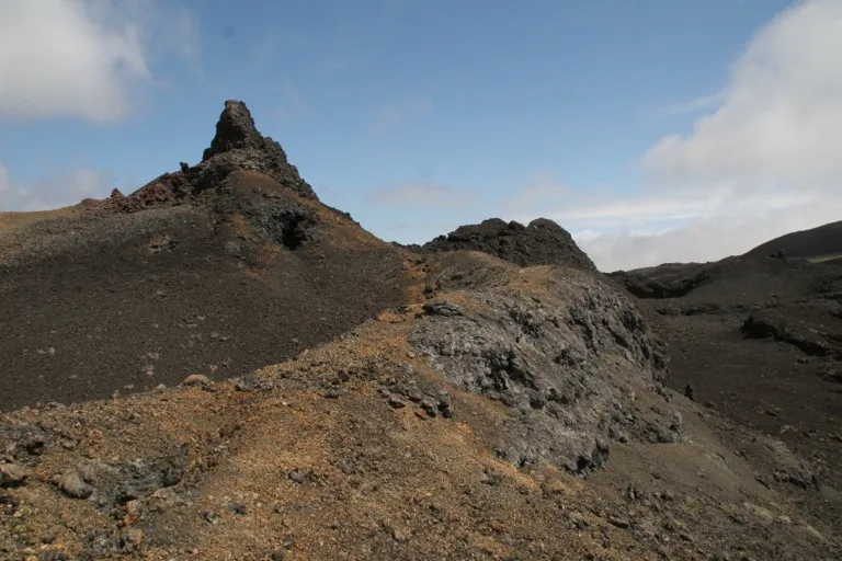 Black lava flows and a jagged volcanic spire on the slopes of Sierra Negra, Isabela