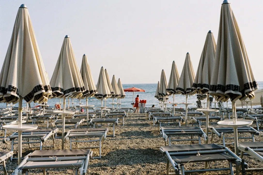 Rows of closed beach umbrellas on an Italian beach at dawn