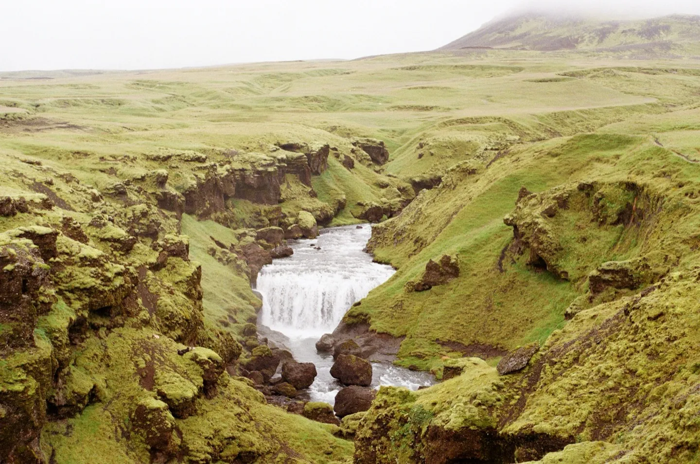 Waterfall cutting through a mossy green canyon in Iceland