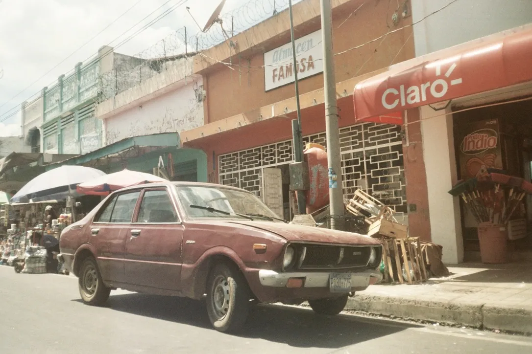 Old red car parked on a colourful Central American street