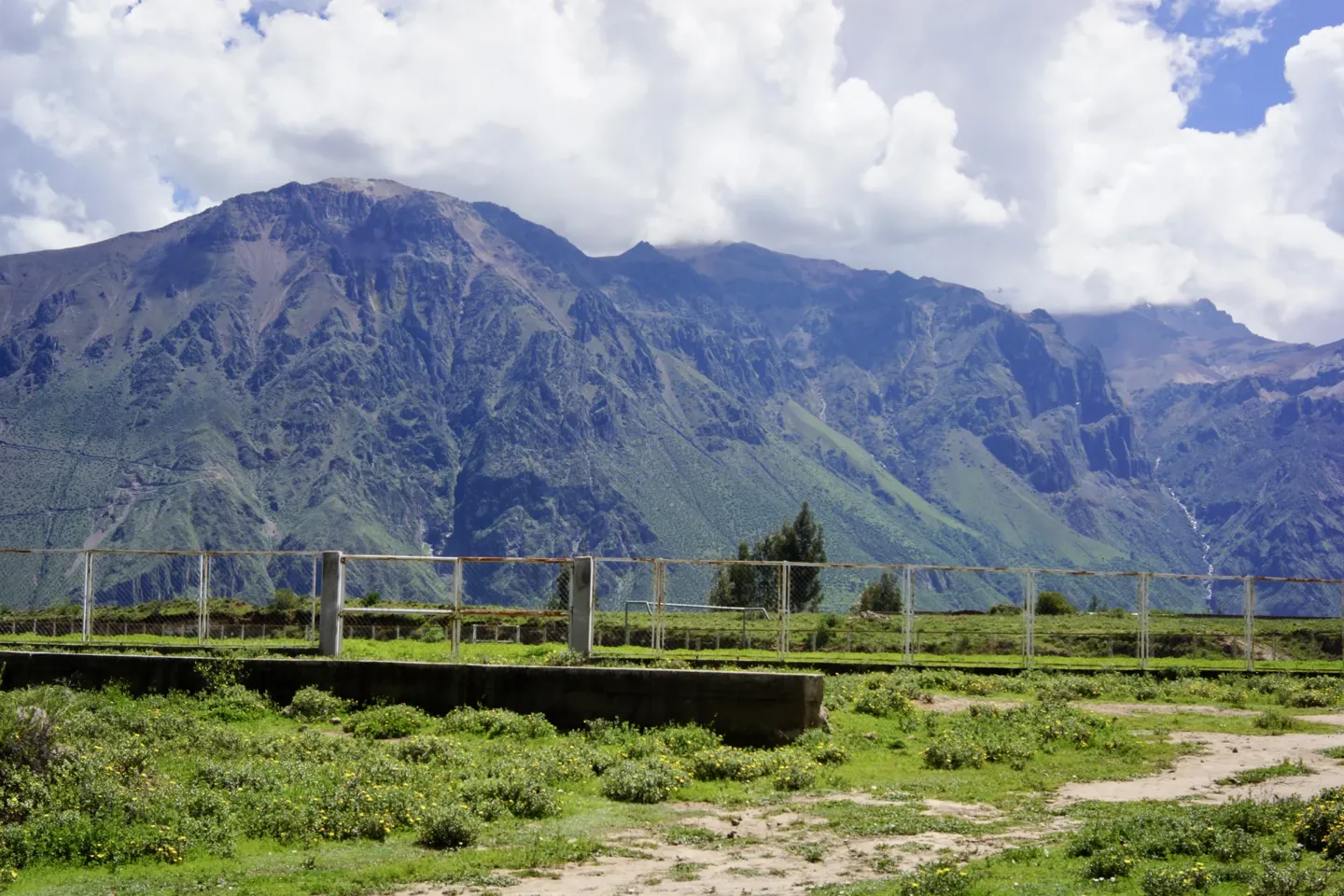 Grassy football field at Cabanaconde with the Colca Canyon walls behind, near the start of the Colca Canyon trek trailhead