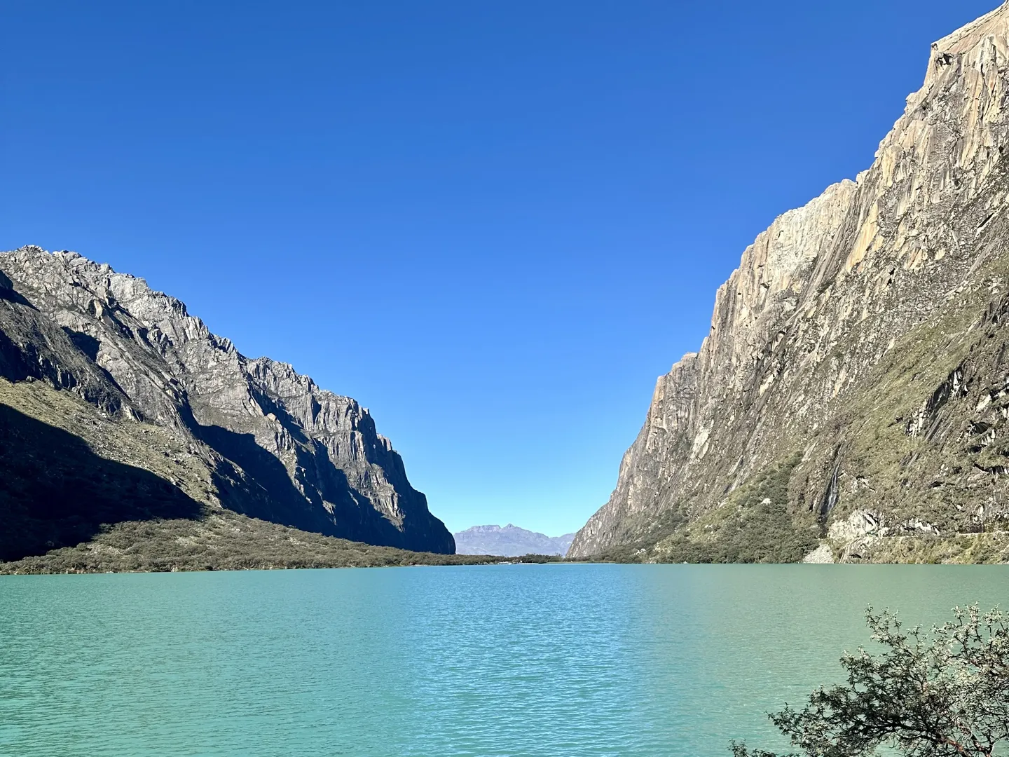 One of the Llanganuco Lakes, bright turquoise water held between steep granite walls on the drive to the Laguna 69 trailhead