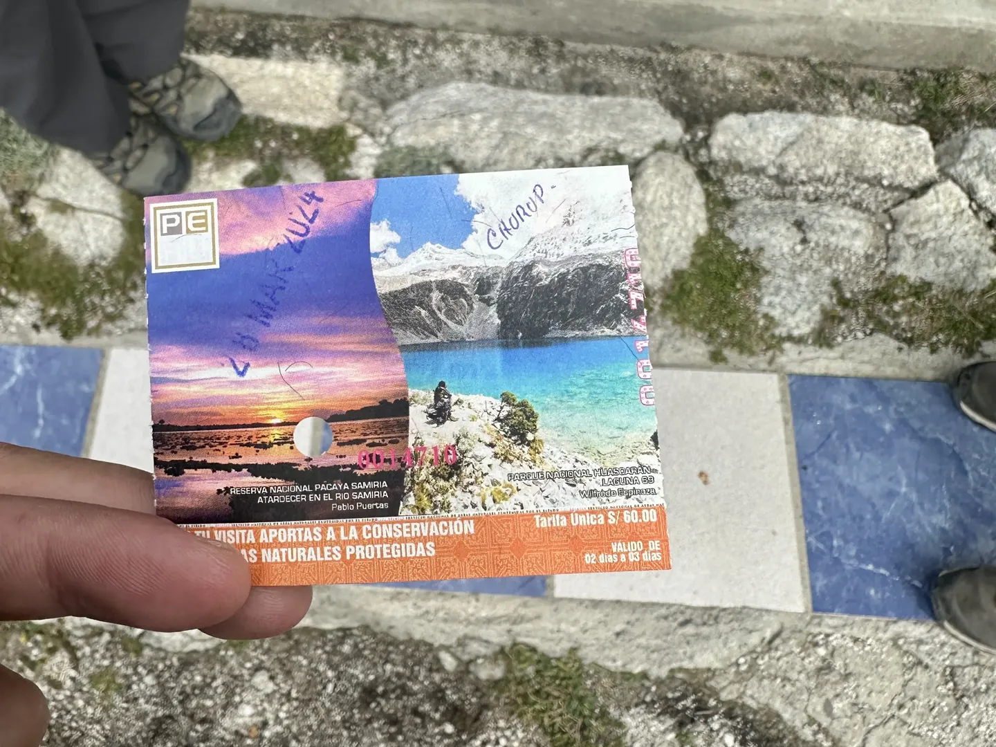 A Huascar&aacute;n National Park entrance ticket marked Churup, held above the cobbles before the Laguna Churup hike