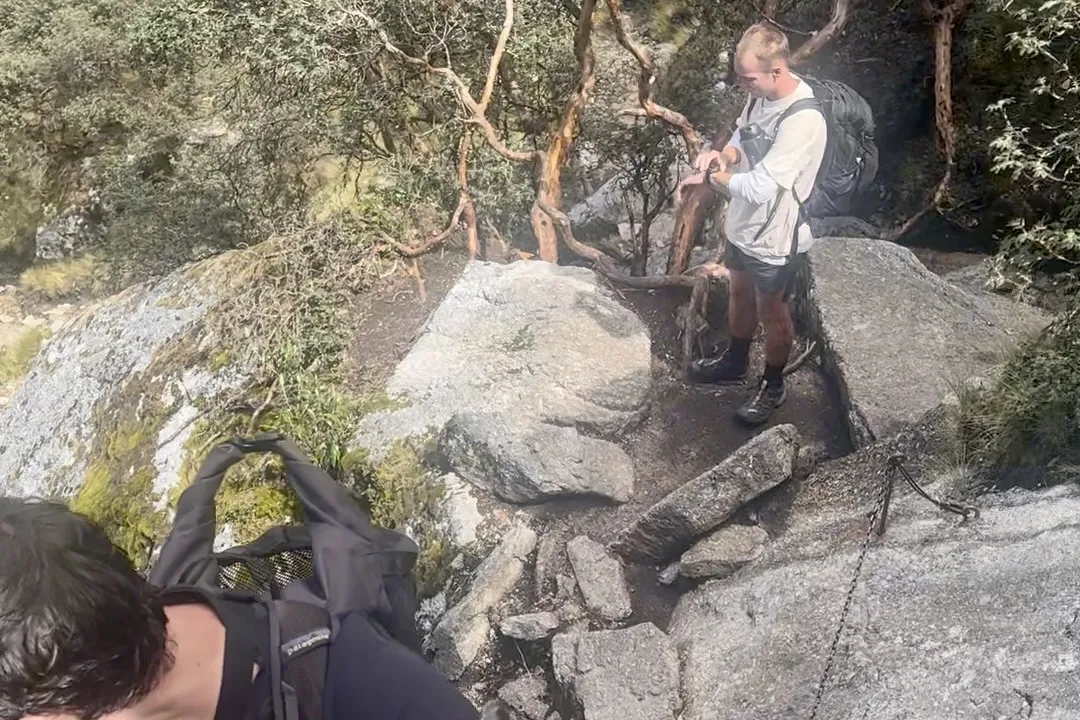 A hiker on the chain-assisted rock scramble near the top of the Laguna Churup hike