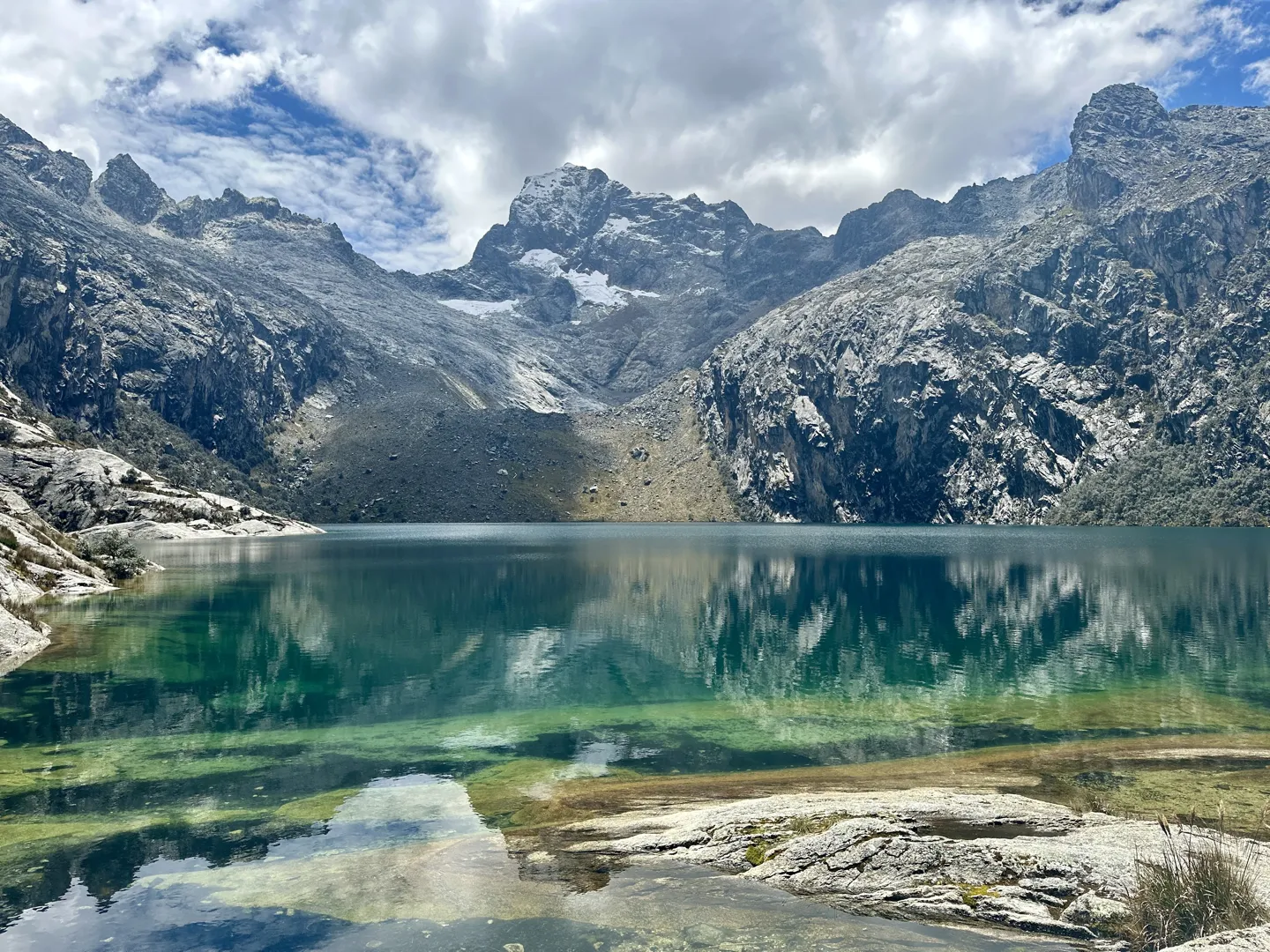 The turquoise shallows of Laguna Churup below jagged snow-capped peaks in Peru&rsquo;s Cordillera Blanca